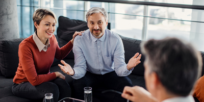 A couple sits with an advisor in a comfortable office setting, discussing financial and estate planning options during a profess
